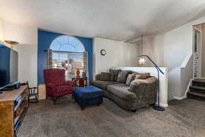 Living room featuring carpet, a textured ceiling, and stairs