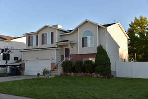 Split foyer home with an attached garage, concrete driveway, and brick siding