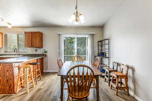 Dining room featuring light wood finished floors, a textured ceiling, and a chandelier