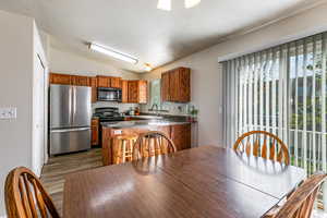 Kitchen with black appliances, vaulted ceiling, dark countertops, a peninsula, and a textured ceiling
