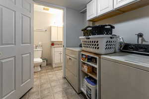 Washroom with cabinet space, light tile patterned flooring, and independent washer and dryer
