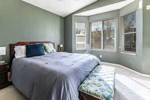Carpeted bedroom with vaulted ceiling and a ceiling fan