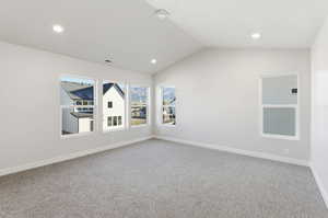 Spare room featuring vaulted ceiling, light colored carpet, and recessed lighting