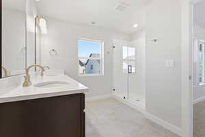 Bathroom featuring double vanity, a shower stall, light tile patterned floors, and recessed lighting