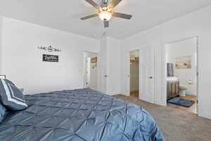 Carpeted bedroom with ceiling fan, a spacious closet, and connected bathroom