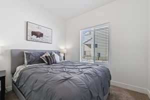 Bedroom featuring dark carpet and baseboards