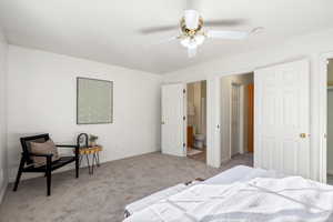 Carpeted bedroom with connected bathroom and a ceiling fan