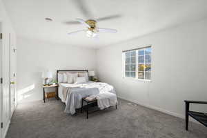 Carpeted bedroom with a ceiling fan and baseboards