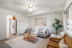 Living room featuring carpet flooring, ceiling fan, and arched walkways