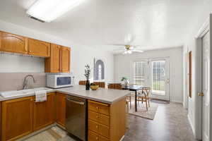 Kitchen featuring dishwasher, light countertops, brown cabinets, a peninsula, and a textured ceiling