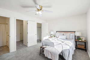 Bedroom with carpet floors, ceiling fan, and a walk in closet