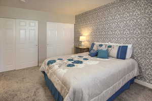 Carpeted bedroom with wallpapered walls and an accent wall