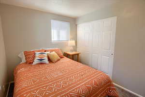 Bedroom with a textured ceiling, a closet, and carpet