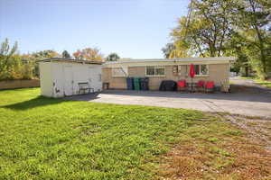 Back of house with a yard, a patio area, brick siding, and a storage unit