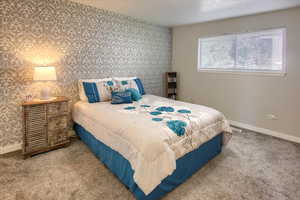 Carpeted bedroom with wallpapered walls and an accent wall