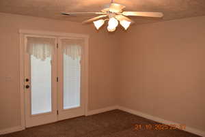 Carpeted empty room featuring a ceiling fan and a textured ceiling