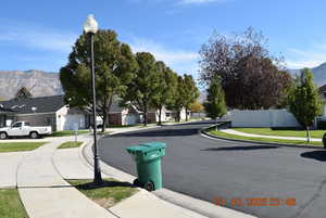 View of asphalt road featuring a mountain view, street lighting, sidewalks, curbs, and a residential view