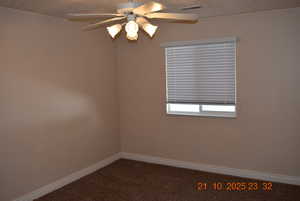 Empty room with carpet, a ceiling fan, and a textured ceiling