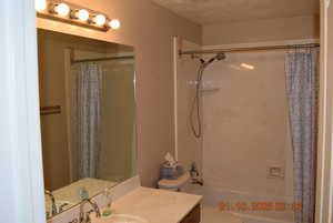 Full bathroom featuring shower / bath combo, a textured ceiling, and vanity