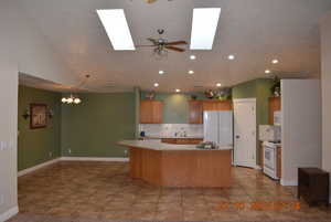 Kitchen featuring tasteful backsplash, ceiling fan, light countertops, a center island, and recessed lighting