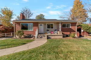 View of front of house featuring a chimney, brick siding, and a porch