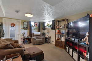 Carpeted living room featuring a textured ceiling