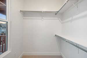 Walk in closet with light colored carpet