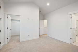 Unfurnished bedroom featuring lofted ceiling, light carpet, a spacious closet, and recessed lighting
