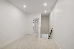 Hallway featuring an upstairs landing, light colored carpet, and recessed lighting
