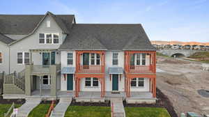 View of front facade with stucco siding, a balcony, roof with shingles, and a mountain view