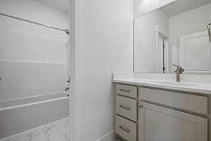 Bathroom featuring vanity, light marble finish floors, and shower / bath combination