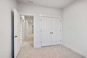 Unfurnished bedroom featuring light carpet and a closet