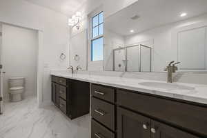 Full bathroom with a shower stall, double vanity, and light marble finish flooring