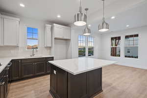 Kitchen with dark brown cabinets, light wood finished floors, light stone counters, and recessed lighting