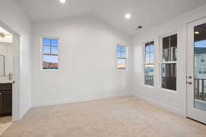 Empty room featuring plenty of natural light, light colored carpet, vaulted ceiling, and recessed lighting