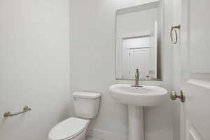 Half bath featuring toilet and baseboards