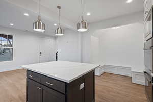 Kitchen with a center island, decorative light fixtures, light wood-type flooring, recessed lighting, and stainless steel appliances