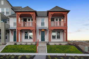 View of front of house featuring stucco siding, a shingled roof, and a front lawn