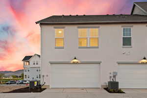 View of front of home featuring concrete driveway, stucco siding, a garage, a shingled roof, and a mountain view
