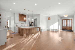 Kitchen with plenty of natural light, brown cabinetry, pendant lighting, french doors, and recessed lighting