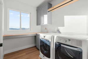 Washroom featuring light wood-type flooring, washing machine and dryer, and cabinet space