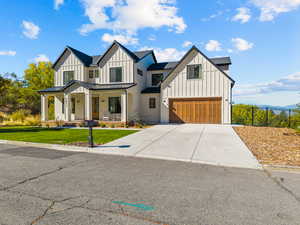 Modern inspired farmhouse featuring board and batten siding, a standing seam roof, a porch, a metal roof, and concrete driveway