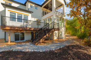 Rear view of house with stucco siding and stairway