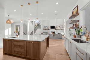 Kitchen featuring pendant lighting, brown cabinets, recessed lighting, open floor plan, and light stone countertops
