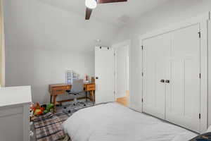 Bedroom with lofted ceiling, an office area, a ceiling fan, a closet, and wood finished floors