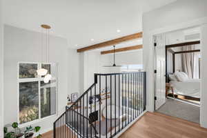 Hallway featuring light wood finished floors, recessed lighting, an upstairs landing, and beam ceiling