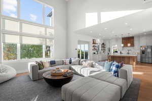 Living room featuring light wood-style flooring, a towering ceiling, and recessed lighting