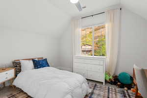 Carpeted bedroom featuring lofted ceiling and ceiling fan
