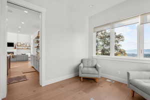 Sitting room with recessed lighting, light wood finished floors, and a lit fireplace