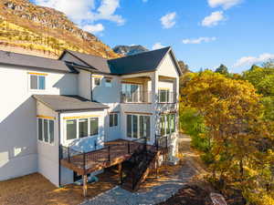 Rear view of property with a balcony, stucco siding, a shingled roof, and a deck with mountain view